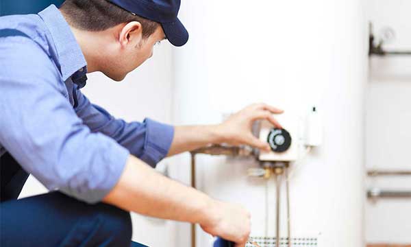 Technician adjusting the control knob of a white water heater.