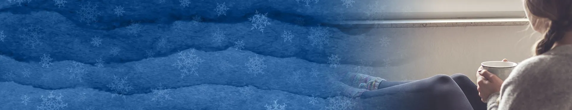 Person sitting by a window holding a cup, with a cold winter scene with snowflakes on the left side.