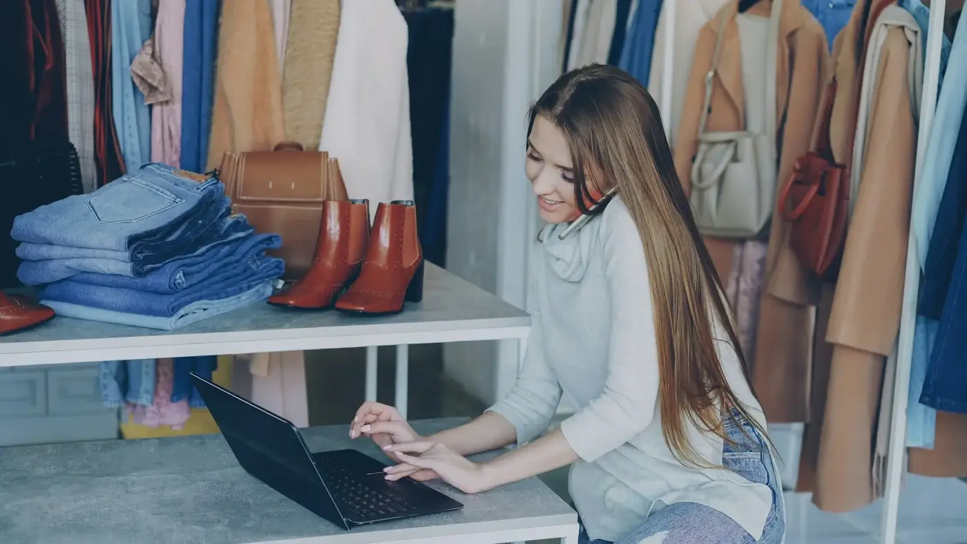Kobieta pracujące na laptopie i rozmawiająca przez telefon w butiku