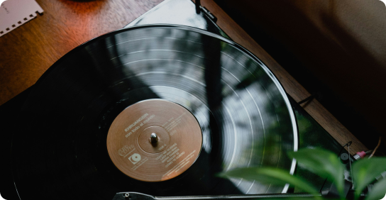 Black vinyl record spinning on a turntable with a wooden surface background.