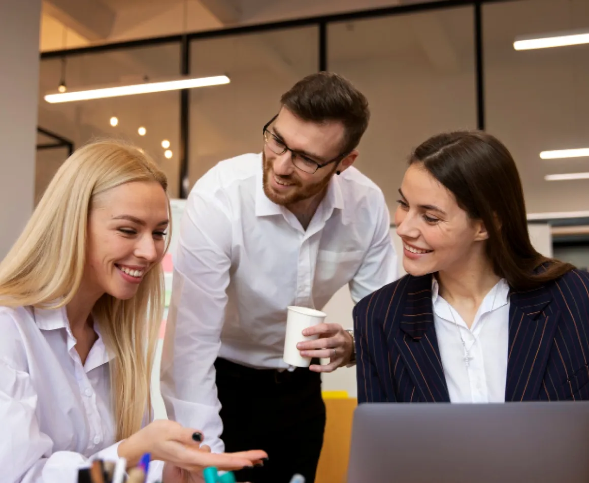 Two women and a man looking at a laptop.