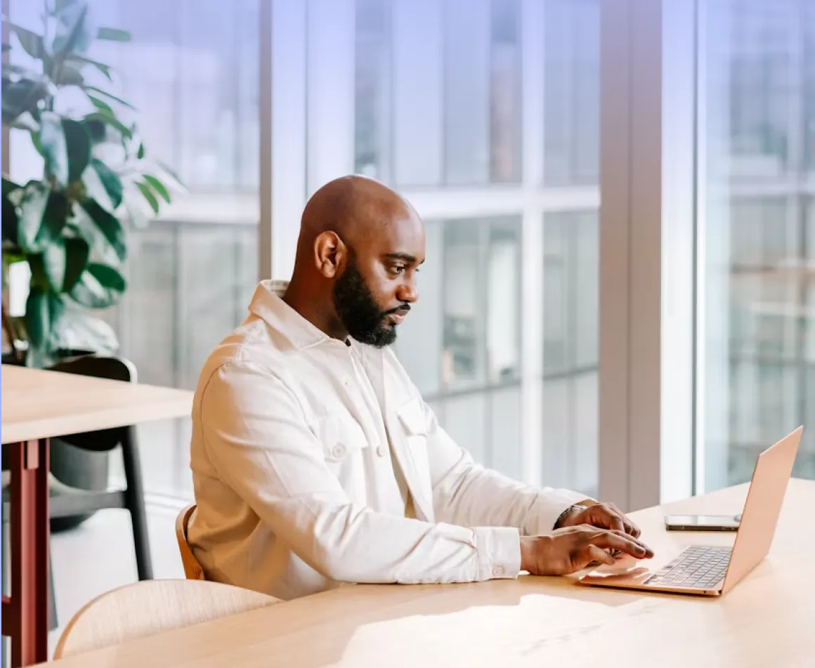 A man sitting at a table using a laptop computer.