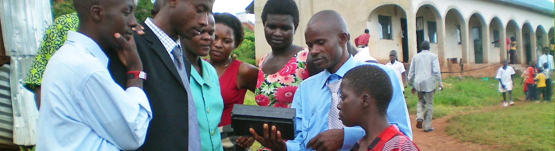 People gathering around a sound device that plays recordings of the Bible.