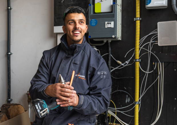 Electrician inspecting high-voltage electrical distribution panel with Circet Energy technician uniform.