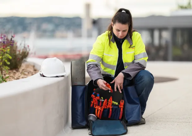 Technician inspecting power tools from energy infrastructure toolkit outdoors.
