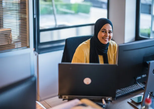 Professional working at desk with laptop, focusing on energy infrastructure and telecommunications projects.