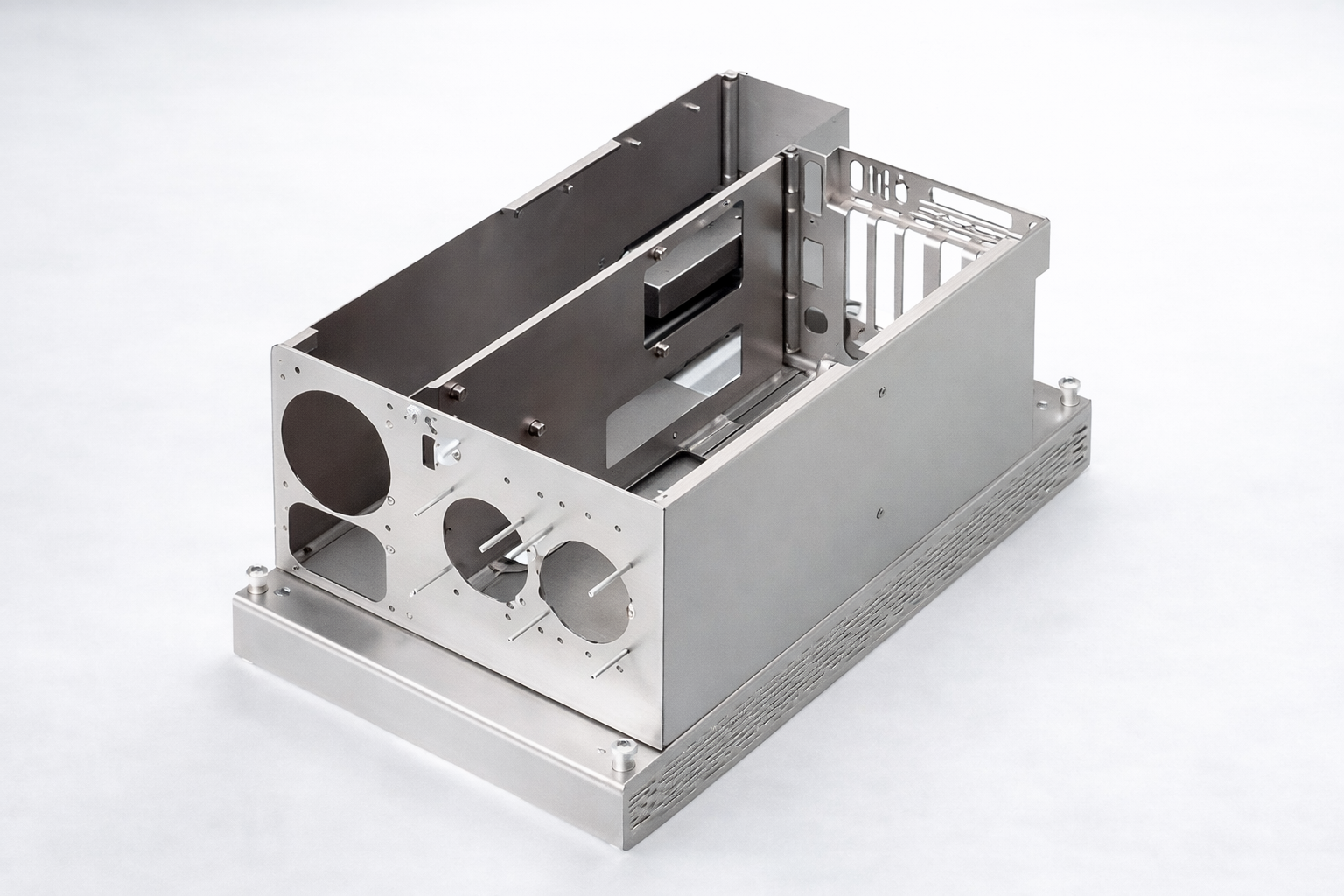 Empty metal computer or electronic device case with ventilation slots and multiple circular cutouts.