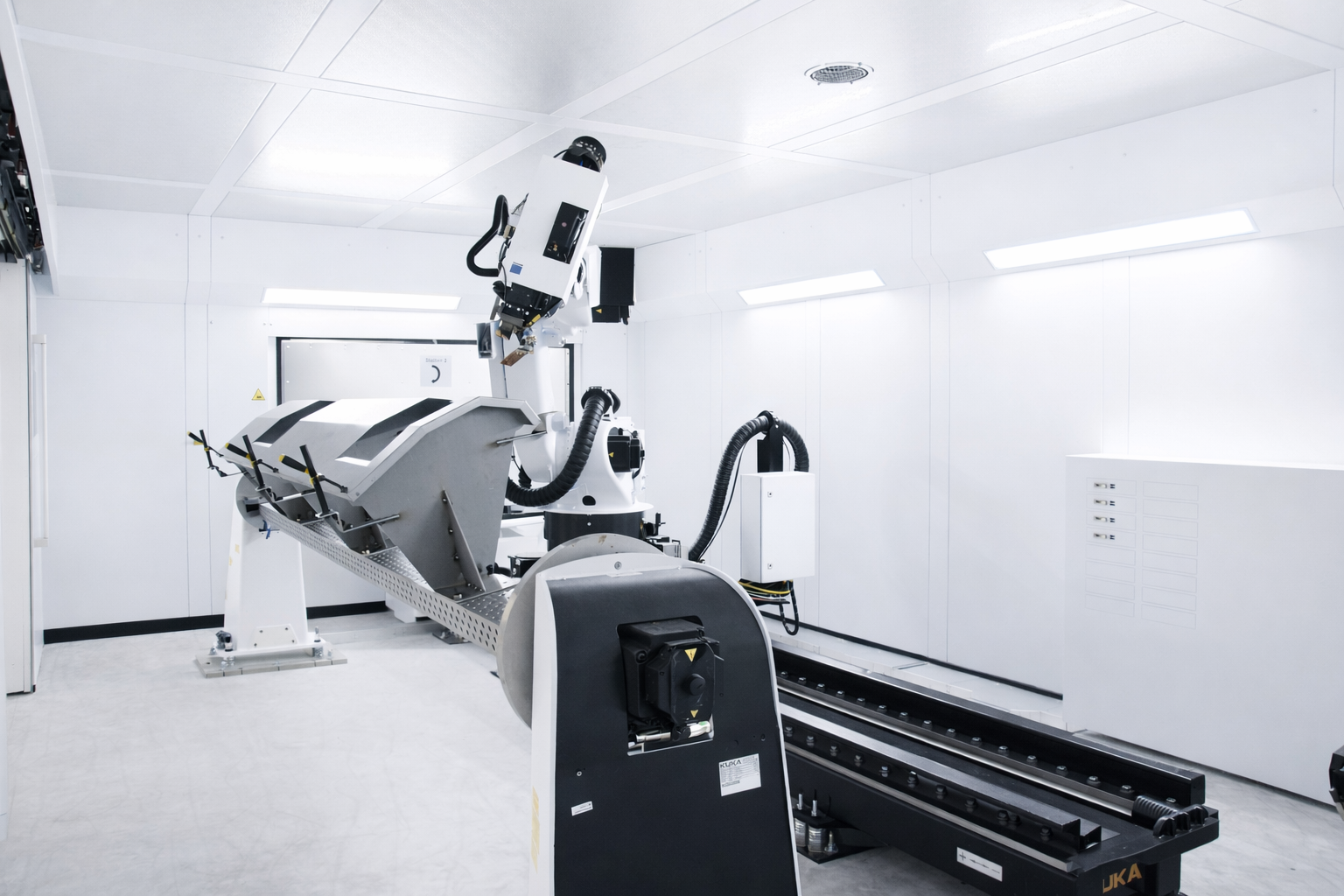 Automated robotic arm in a clean, well-lit industrial room used for manufacturing or assembly.
