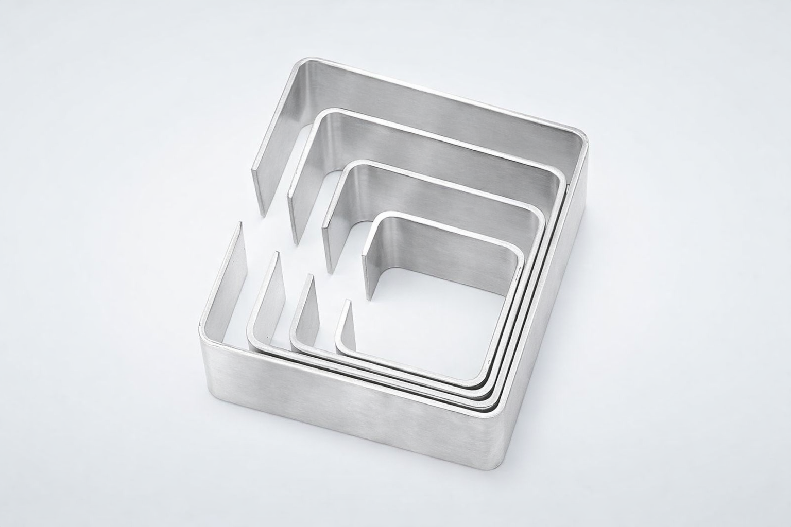 Set of four nested square stainless steel cookie cutters on a white background.