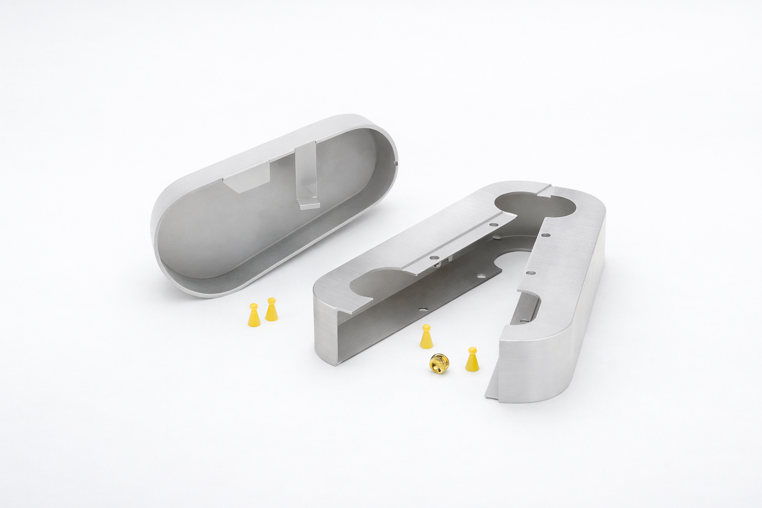 Two open silver metal casing parts with small yellow plastic and one brass component placed on a white surface.