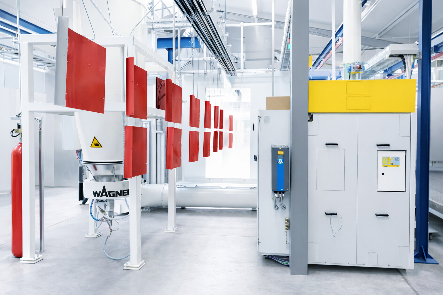 Industrial painting line with red metal parts hanging for coating in a bright, clean factory environment.