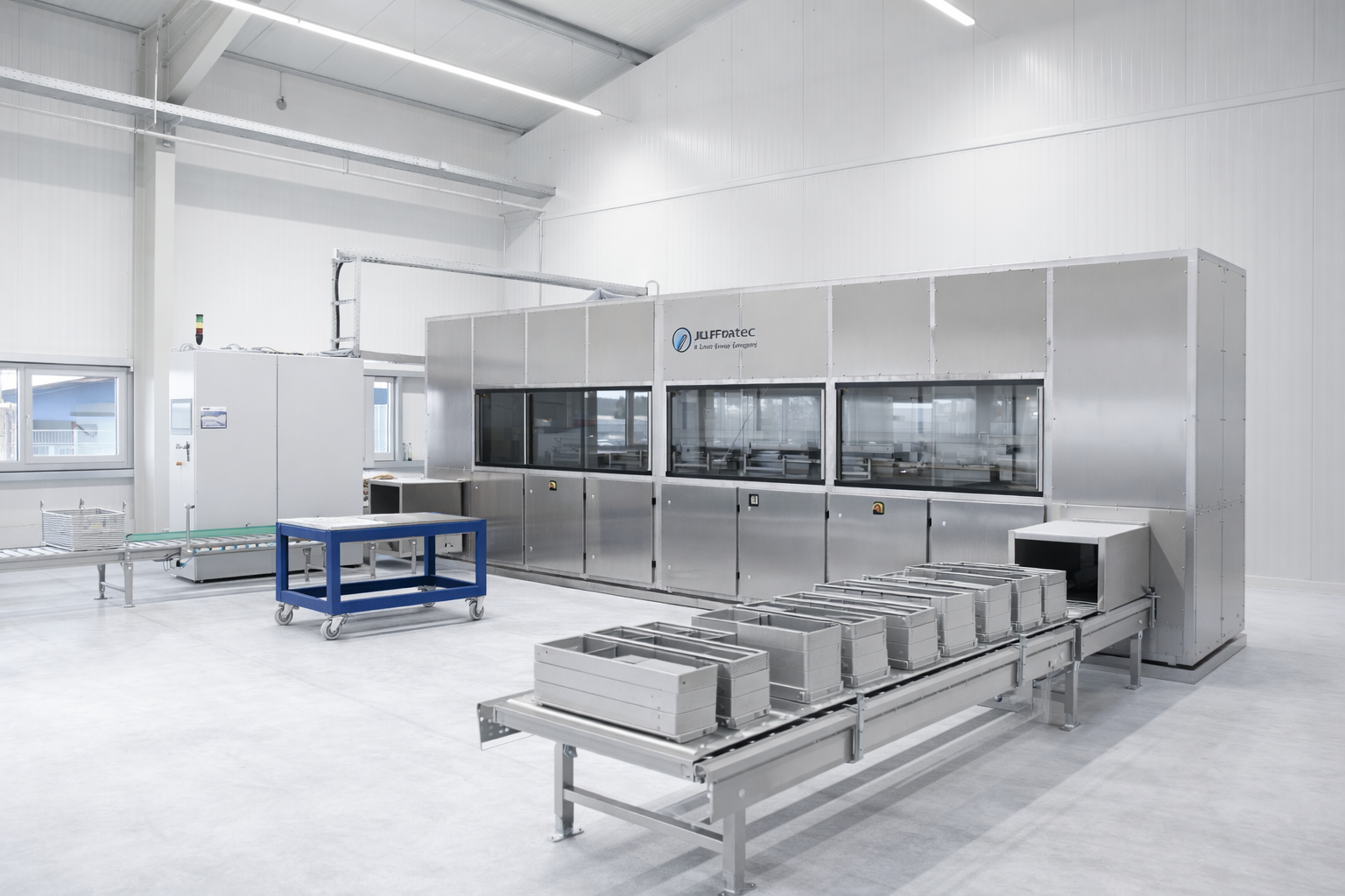 Industrial stainless steel machine with conveyor belts and metal containers in a bright factory setting.