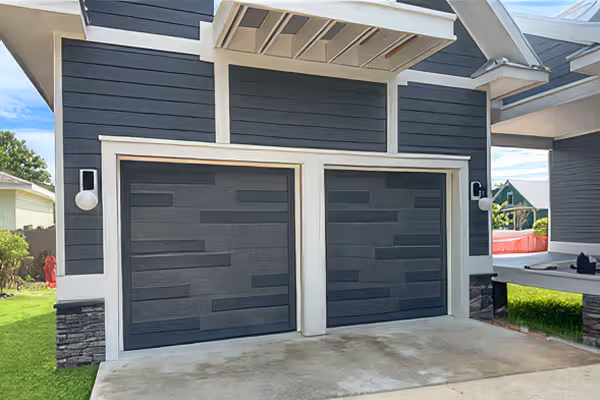Modern house exterior with two dark gray garage doors and stone trim accents.
