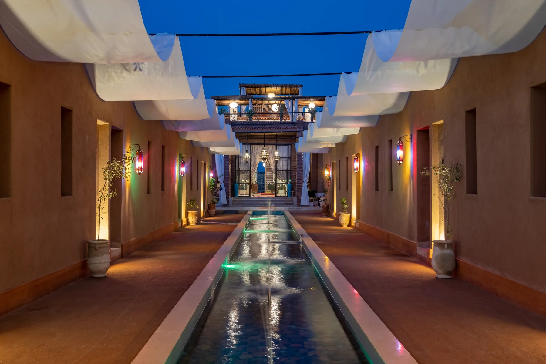 Villa Moira, celebration villa in the Palmeraie, Marrakech, water walkway at blue hour. The Marrakech Curator.