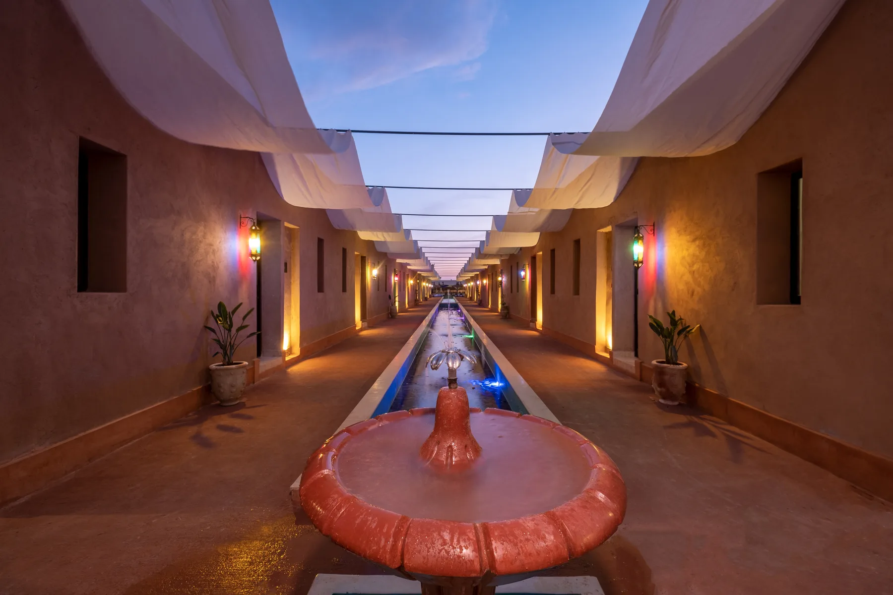 Villa Moira, celebration villa in the Palmeraie, Marrakech, water walkway with fountain at night. The Marrakech Curator.