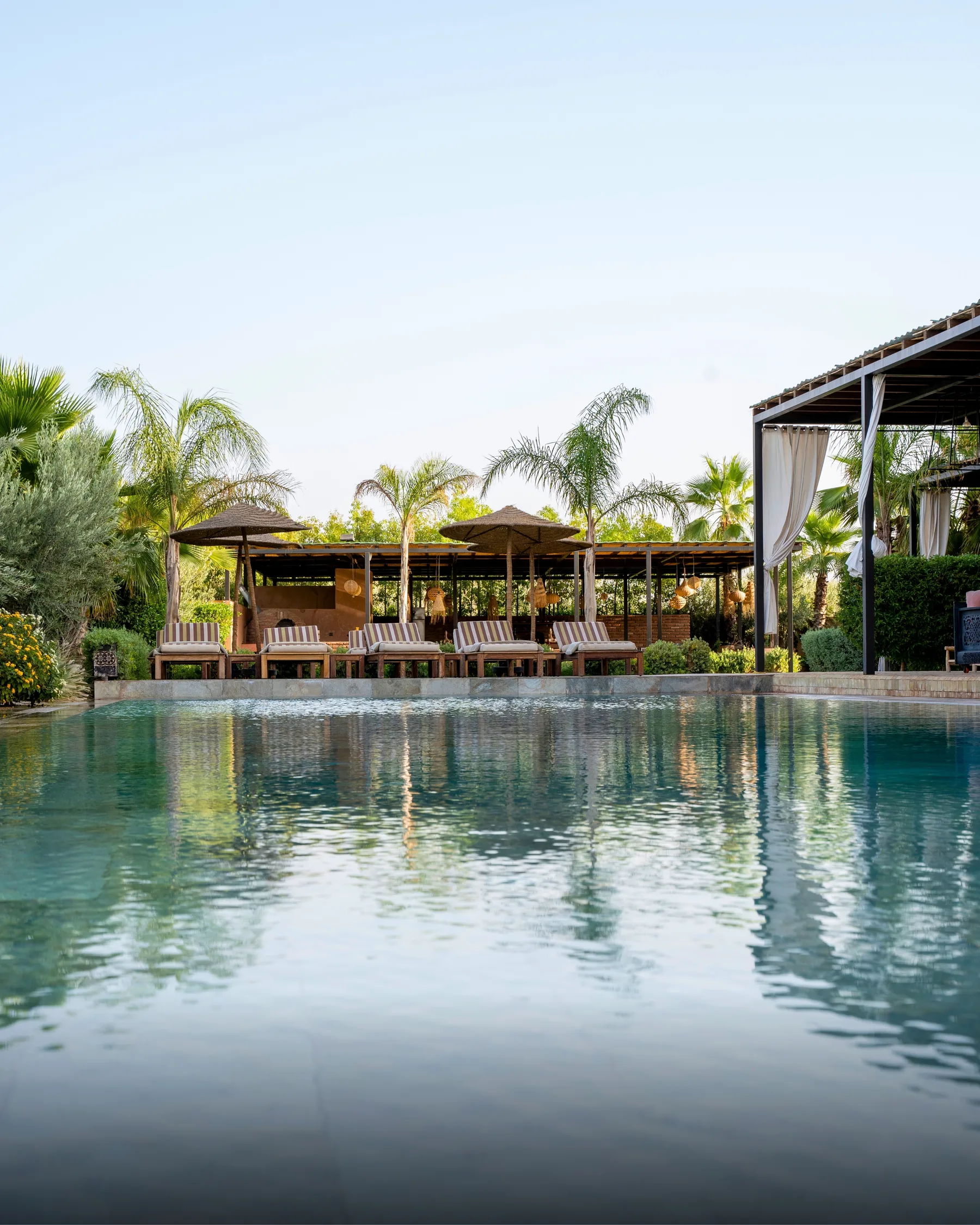 Villa Kallista, 12 bedroom wedding and event villa in Marrakech, heated pool with pergola and palms. The Marrakech Curator.