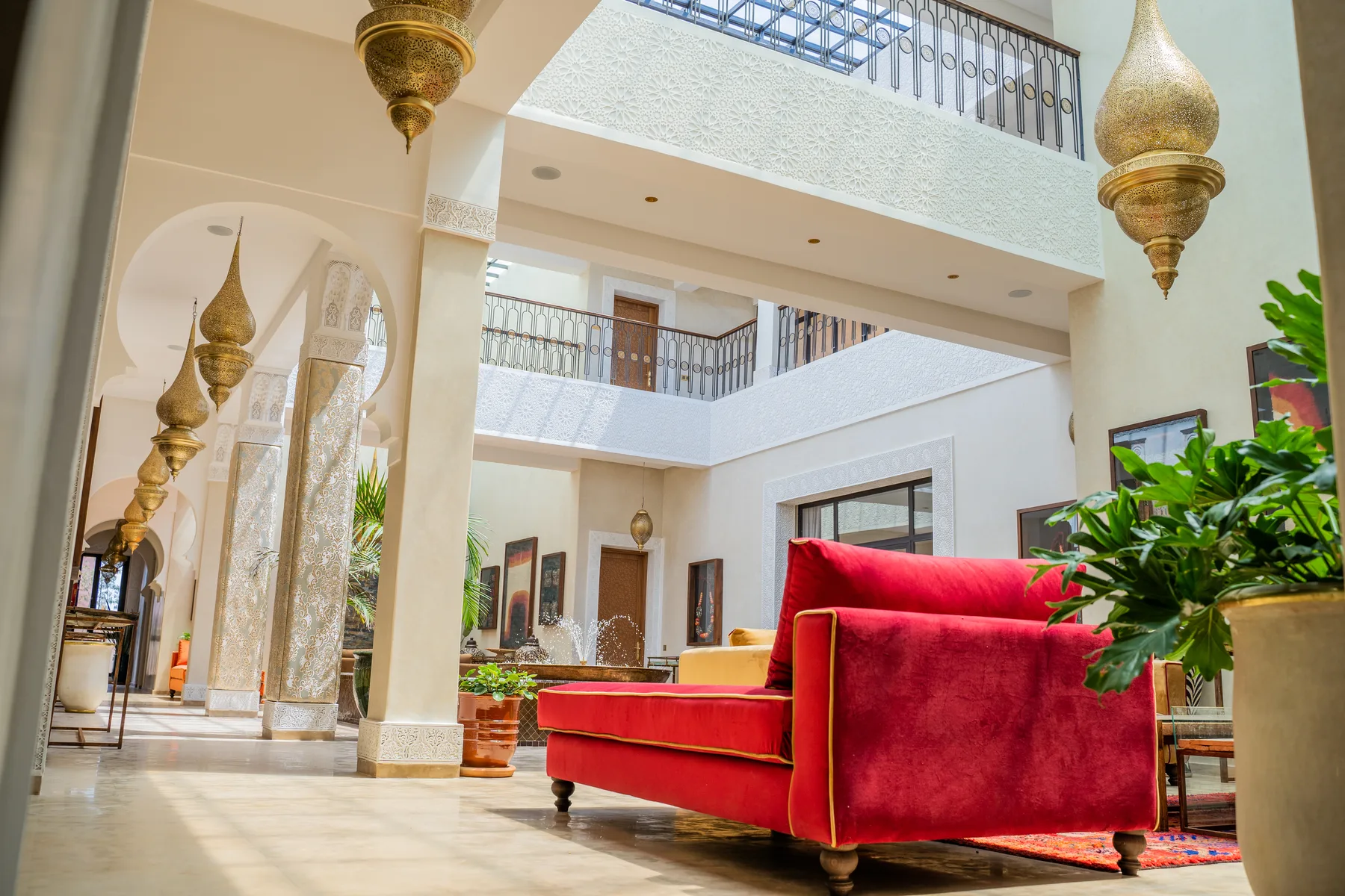 Villa Kallista, 12 bedroom wedding and event villa in Marrakech, double-height patio with red sofa. The Marrakech Curator.
