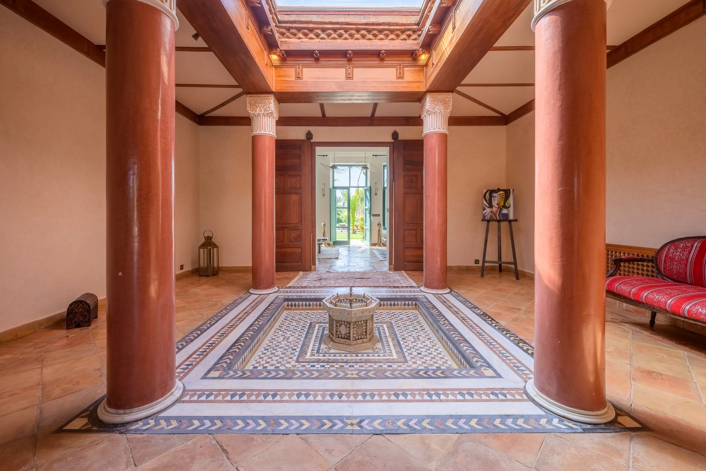 Villa Calypso, private villa rental in the Palmeraie, Marrakech: hall with red columns and mosaic floor