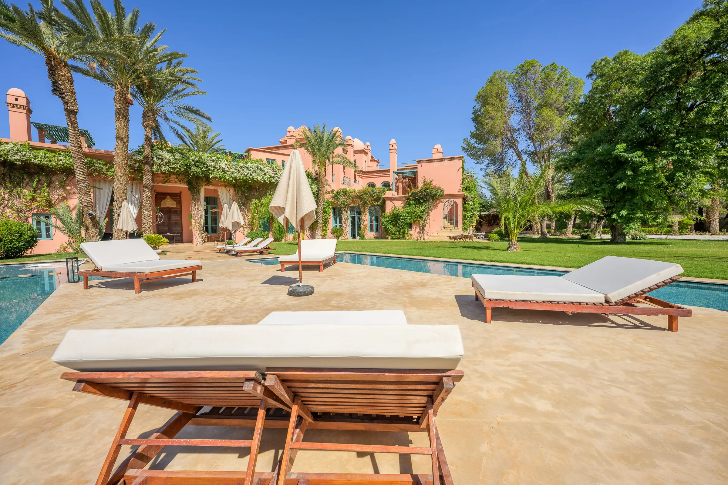 Villa Calypso, private villa rental in the Palmeraie, Marrakech: sun loungers and parasols on the pool deck