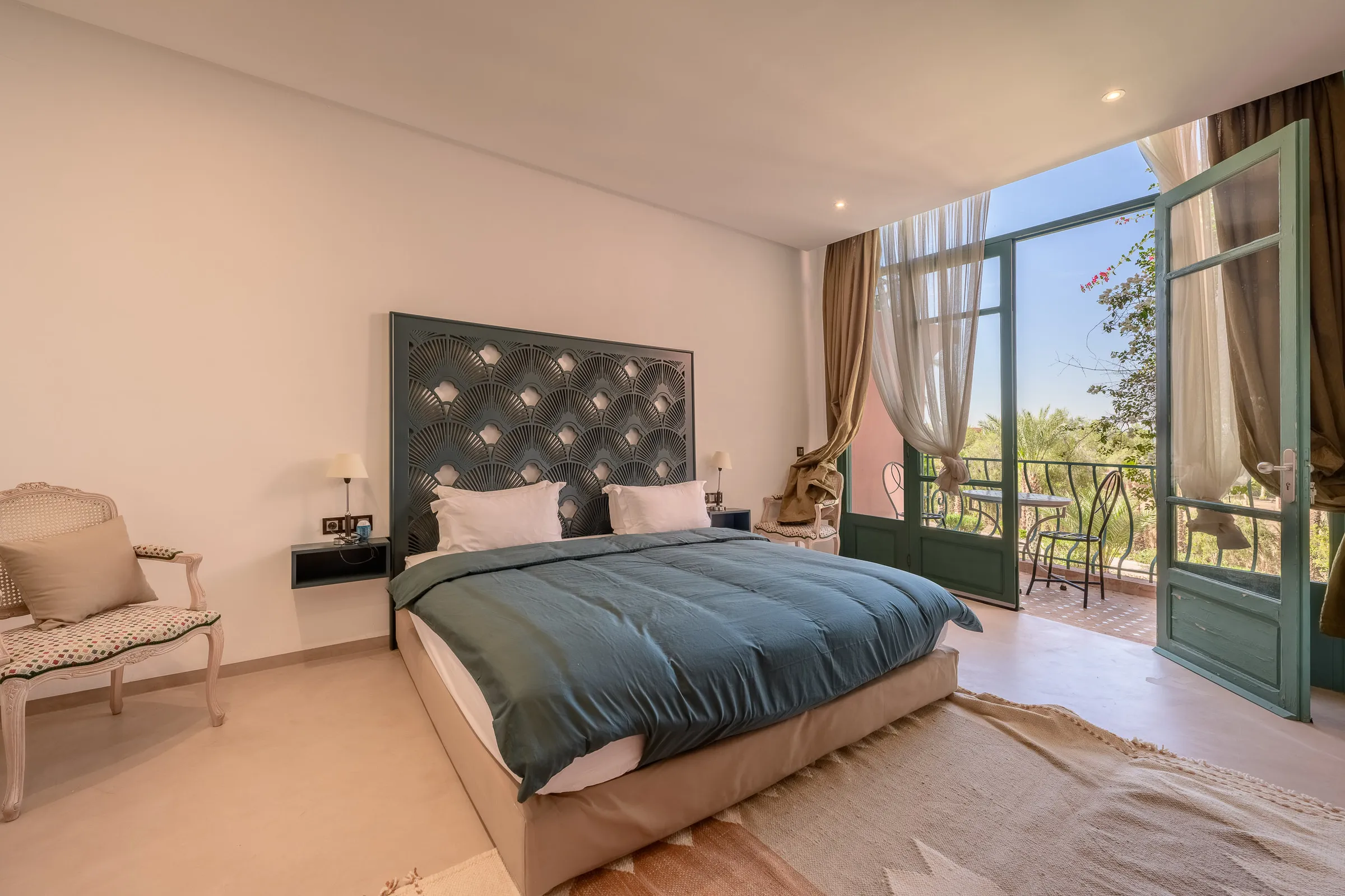 Villa Calypso, private villa rental in the Palmeraie, Marrakech: bedroom with padded headboard opening onto a balcony