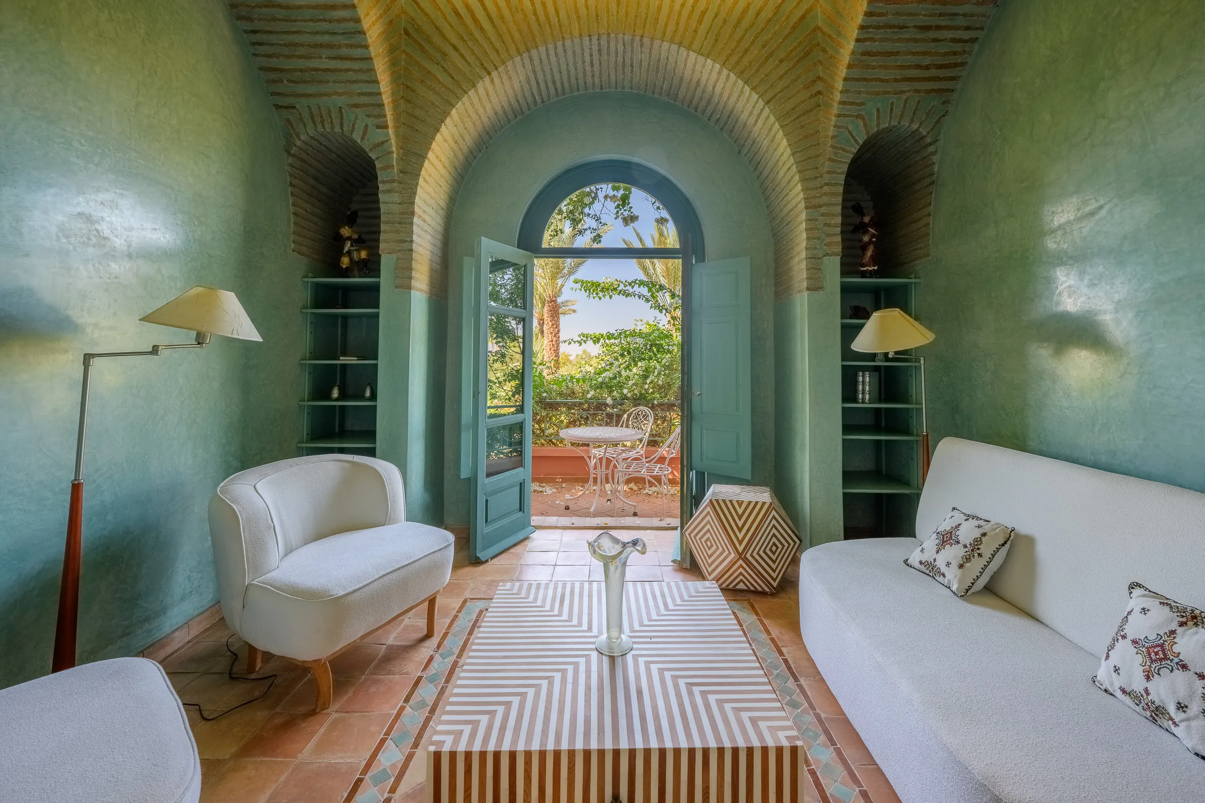 Villa Calypso, private villa rental in the Palmeraie, Marrakech: green sitting room with arched door opening outside