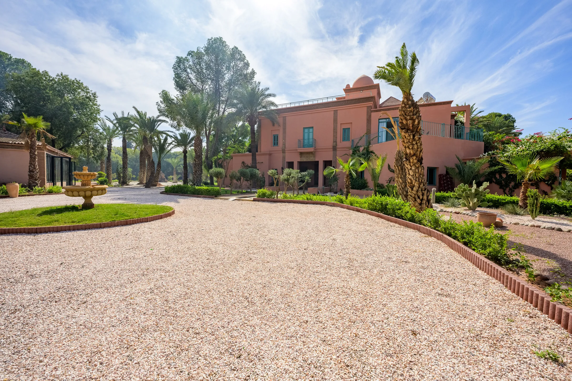 Villa Calypso, private villa rental in the Palmeraie, Marrakech: gravel driveway with fountain in front of the villa