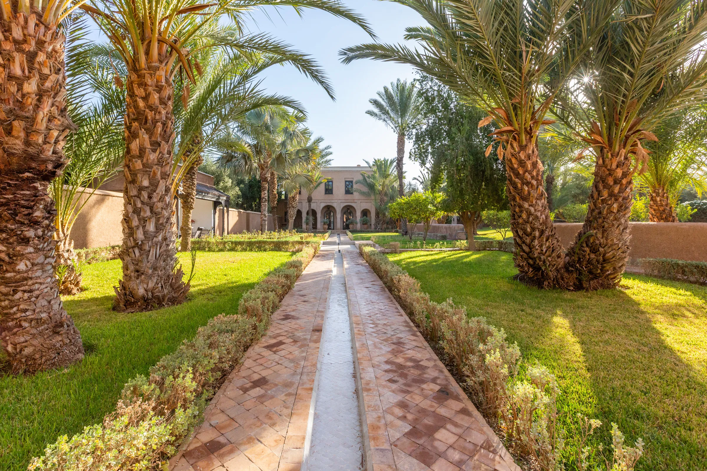 Villa Amalthea, private villa rental in the Palmeraie, Marrakech: garden water channel lined with palm trees