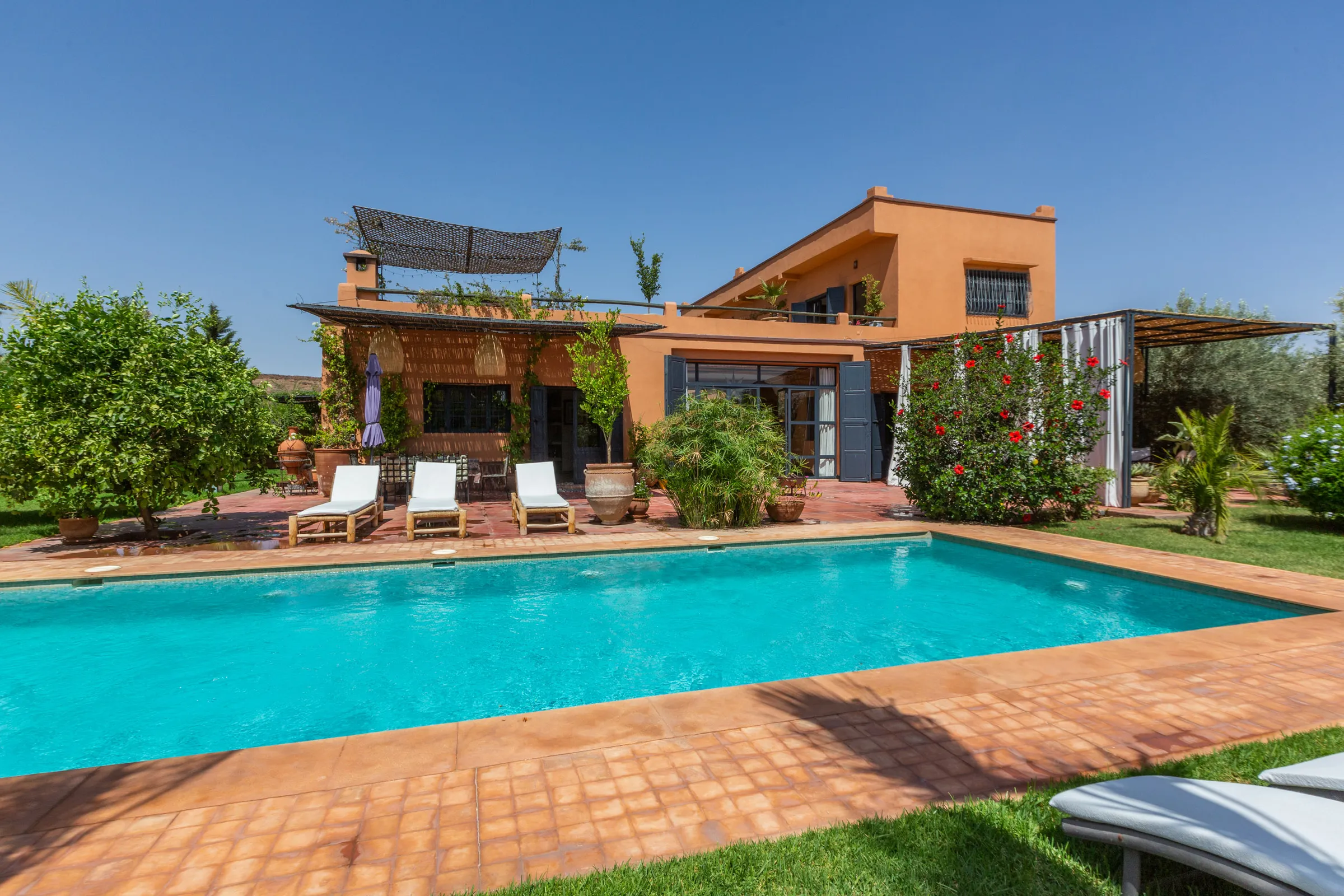 Villa Cassia, private villa rental on the Route de Tahanaout, Marrakech: pool and ochre facade of the villa