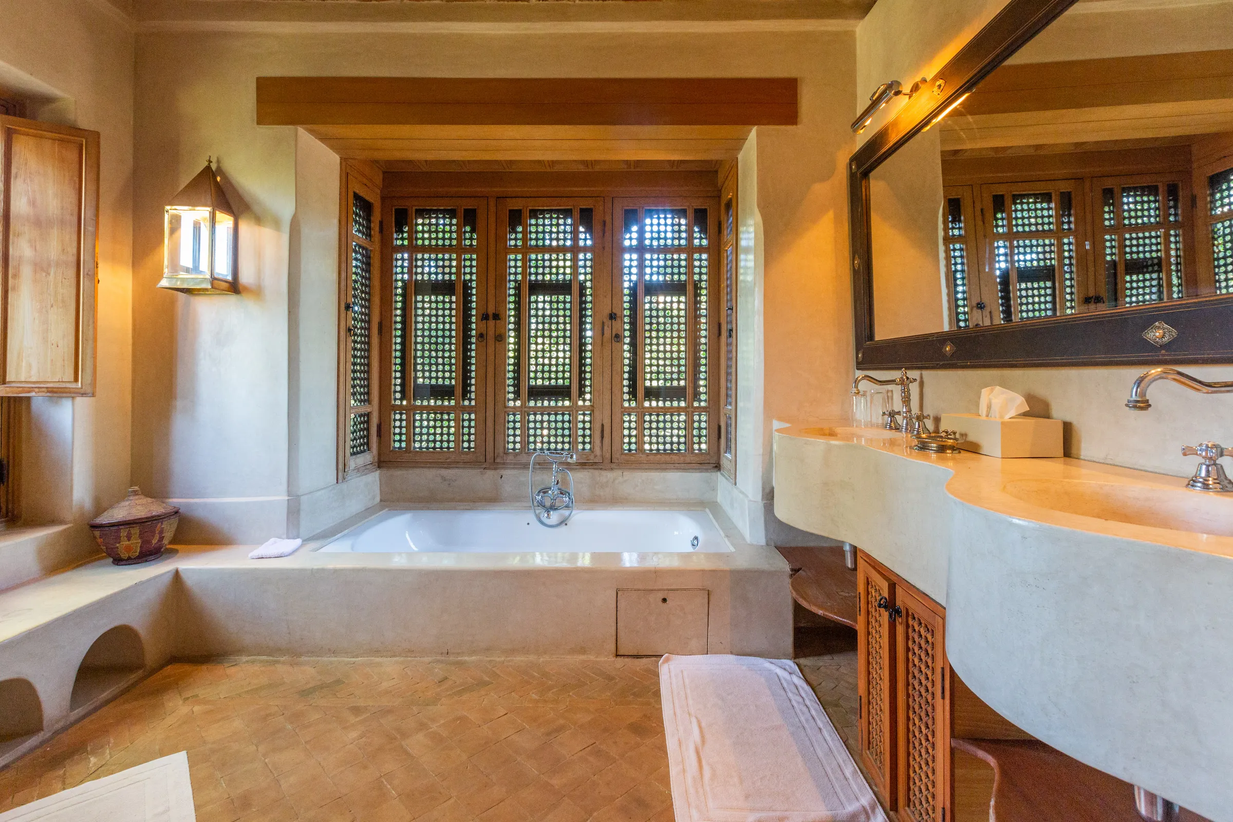 Villa Amalthea, private villa rental in the Palmeraie, Marrakech: bathroom with bathtub beneath a carved wooden window