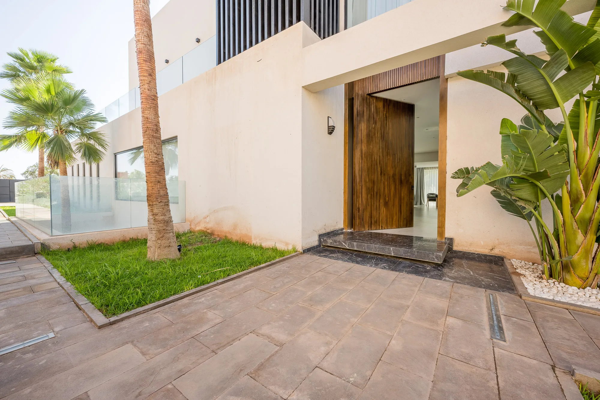 Villa Daphne, private villa rental at Amelkis Golf, Marrakech: entrance with a tall wooden door and tropical plants