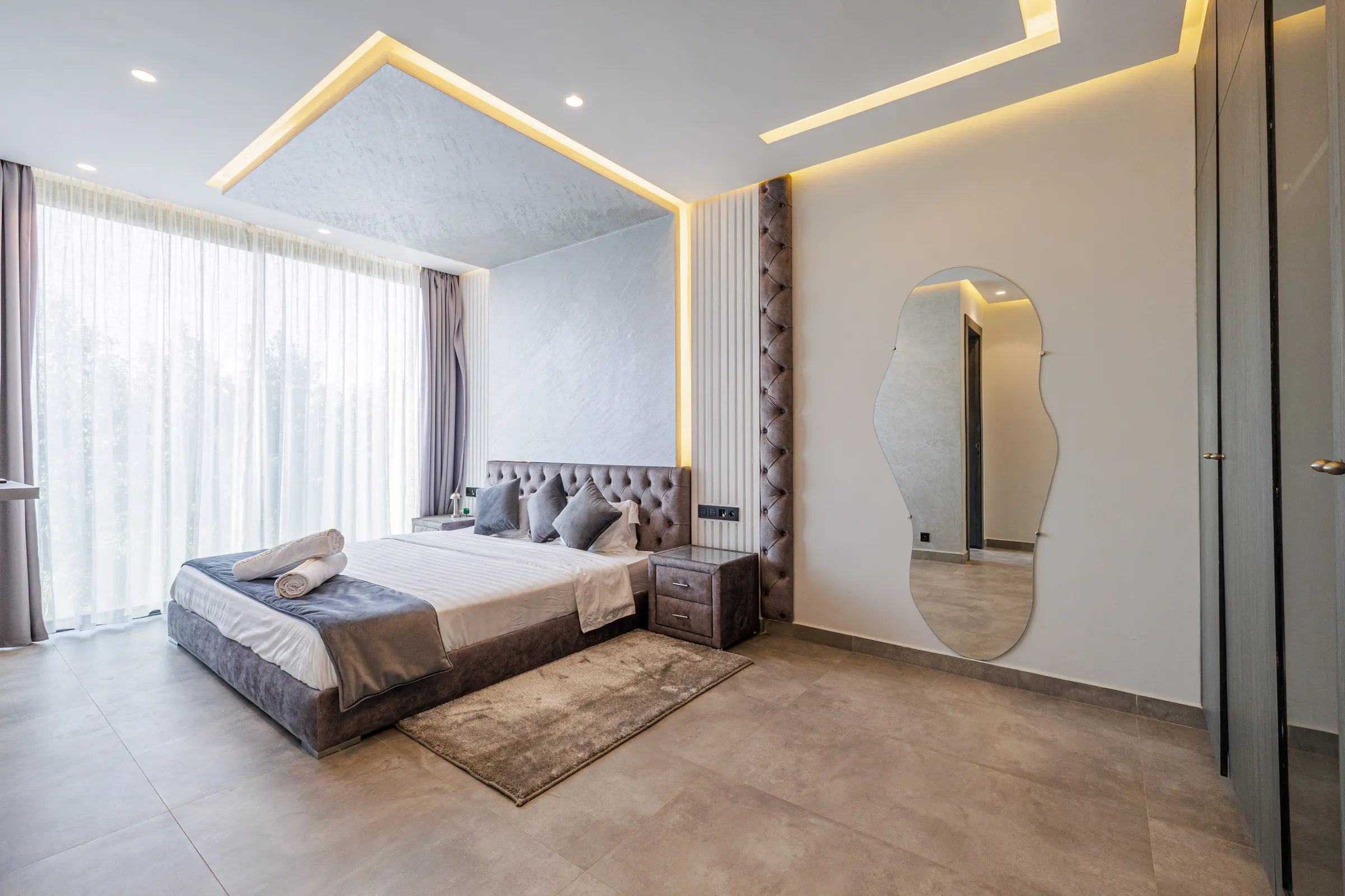 Villa Nefeli, private villa rental at Amelkis Golf, Marrakech: bedroom with tufted headboard and wall mirror