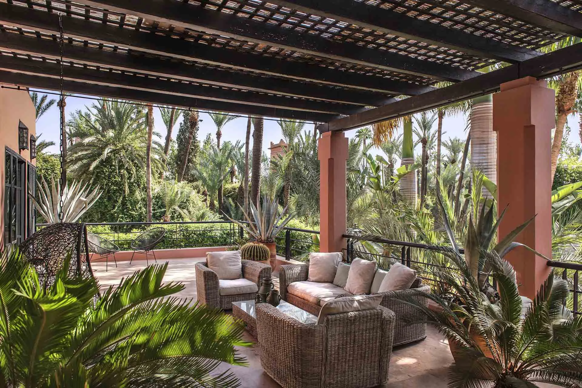 Villa Leda, private villa rental near Majorelle, Marrakech: covered terrace with wicker seating overlooking palm trees
