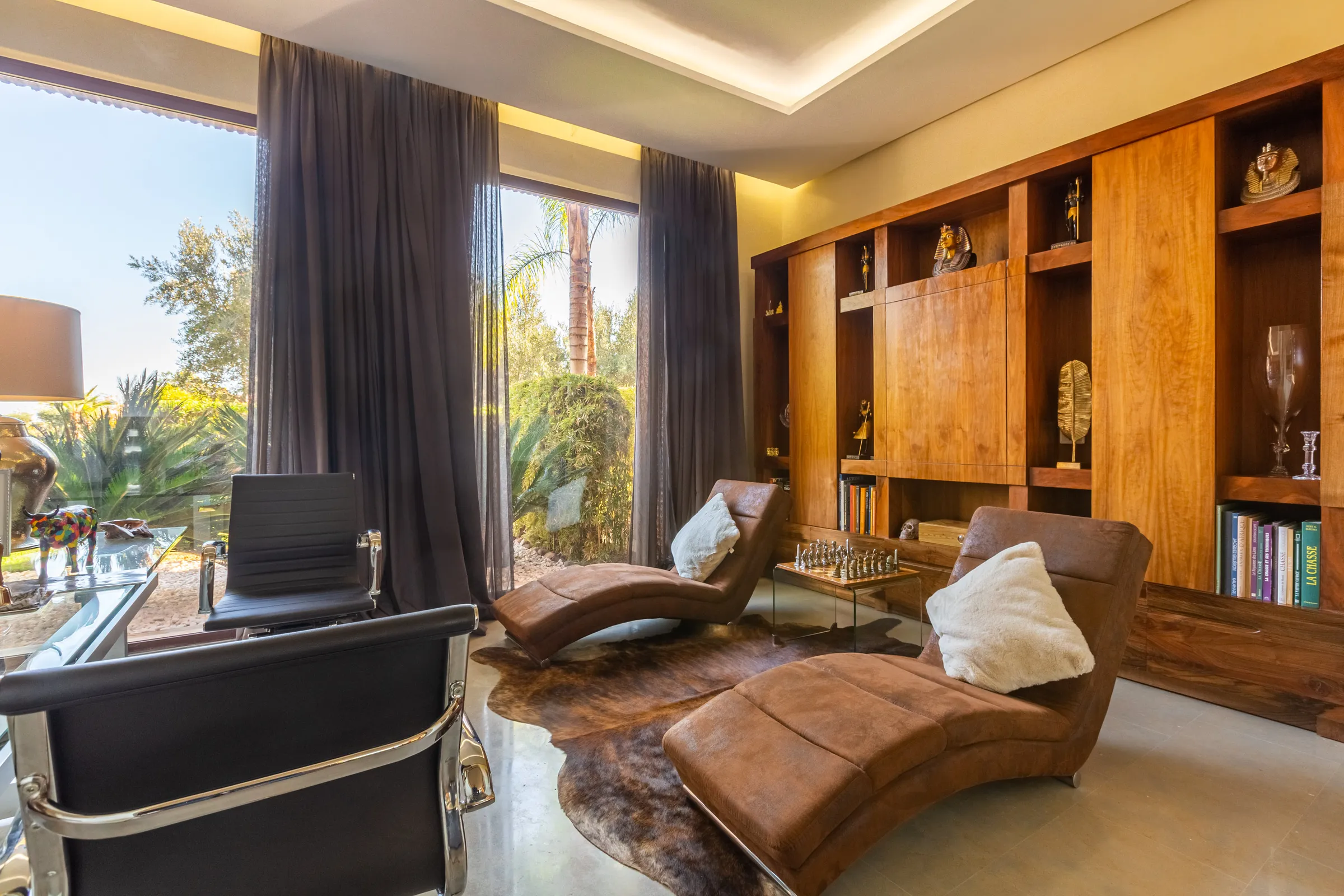 Villa Ismene, private villa rental at Samanah Golf, Marrakech: library corner with lounge chairs and bookshelves