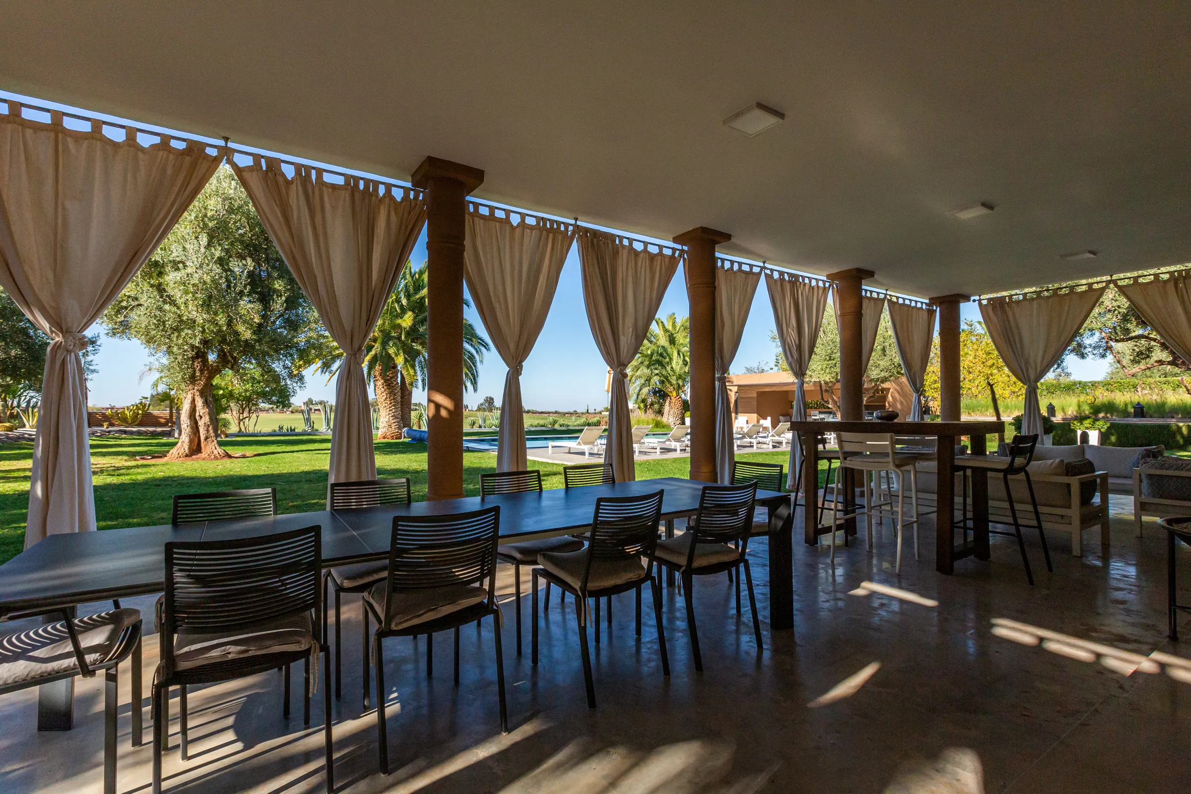 Villa Ismene, private villa rental at Samanah Golf, Marrakech: covered terrace with a long dining table and curtains