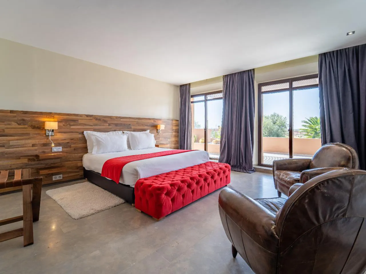 Villa Ismene, private villa rental at Samanah Golf, Marrakech: bedroom with red bench and leather armchairs