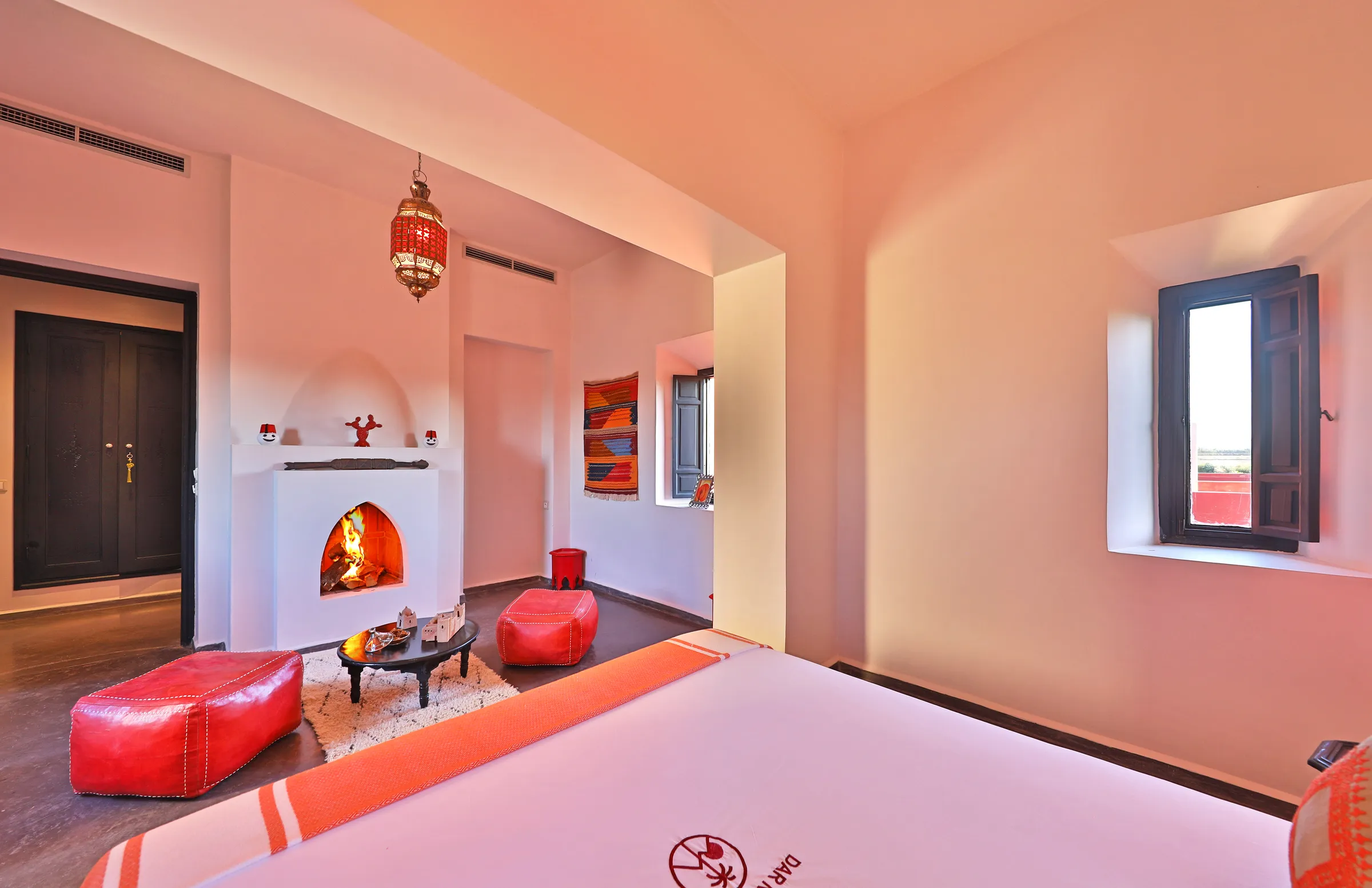 Villa Iliana, private villa rental on the Route de l'Ourika, Marrakech: pink bedroom with fireplace and leather poufs