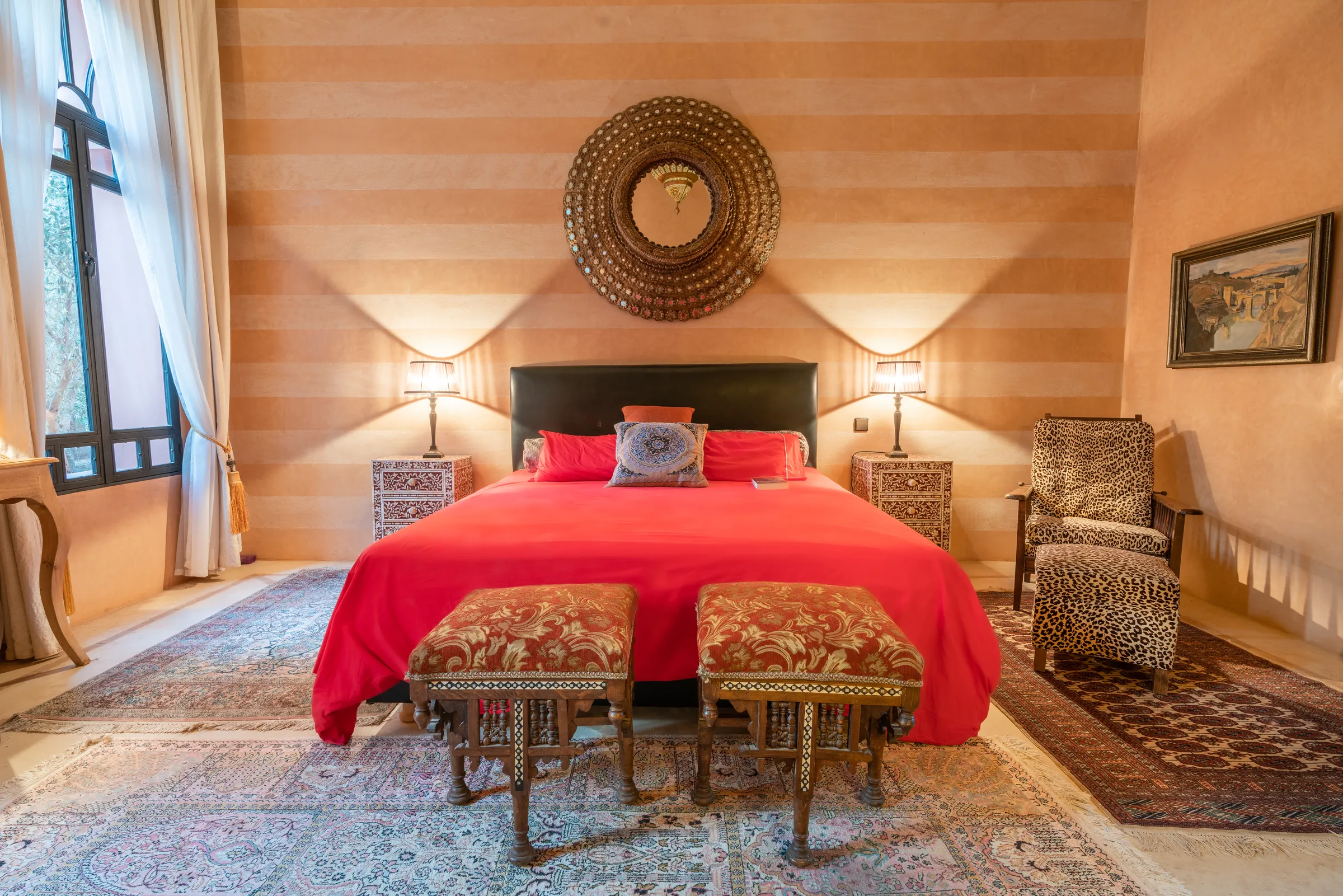 Villa Lyra, private villa rental in Ouled Hassoune, Marrakech: bedroom with red bedspread and round mirror