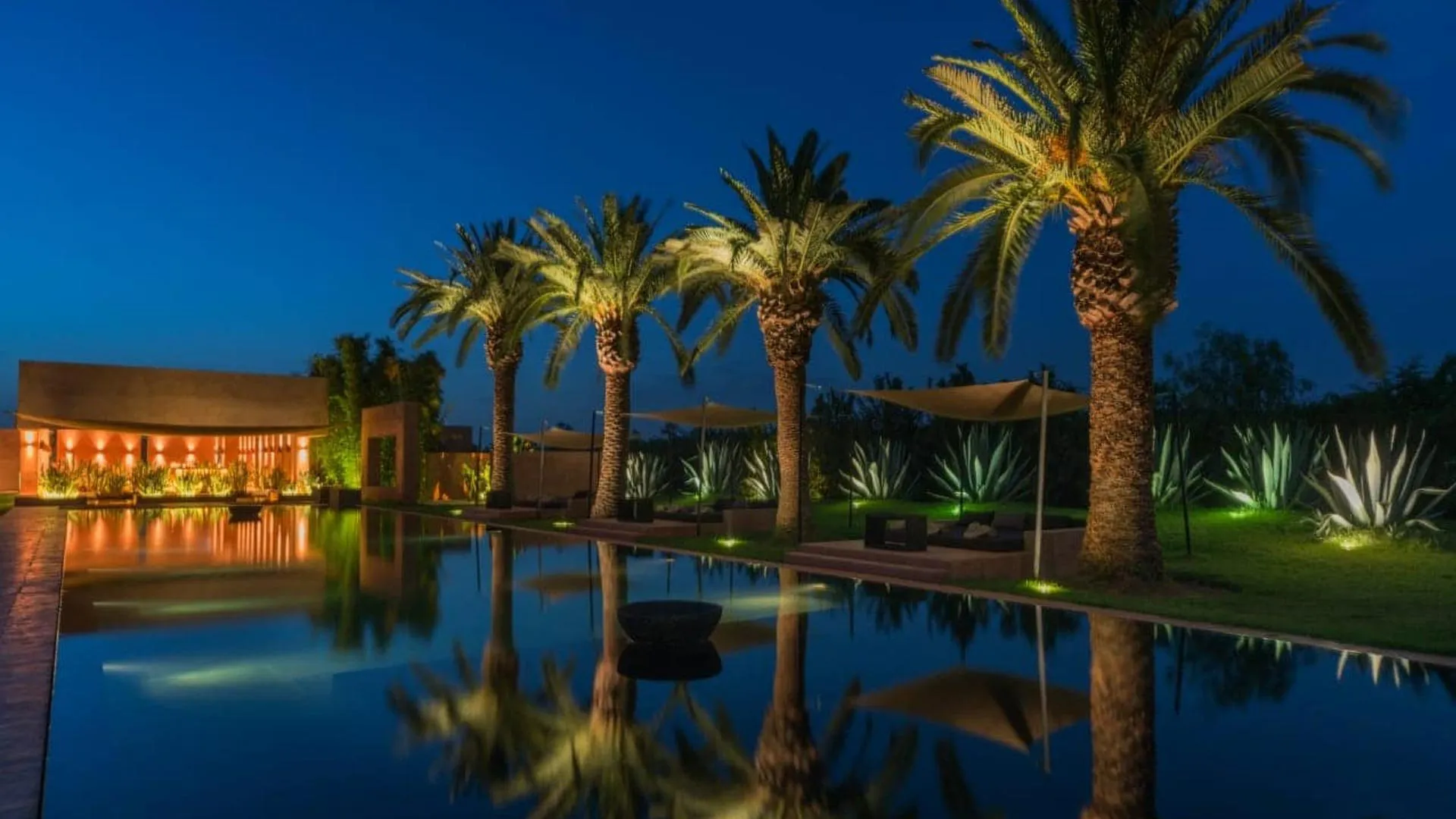 Villa Phaedra, location de domaine privé à Ouled Hassoune, Marrakech : long bassin reflétant les palmiers à l'heure bleue