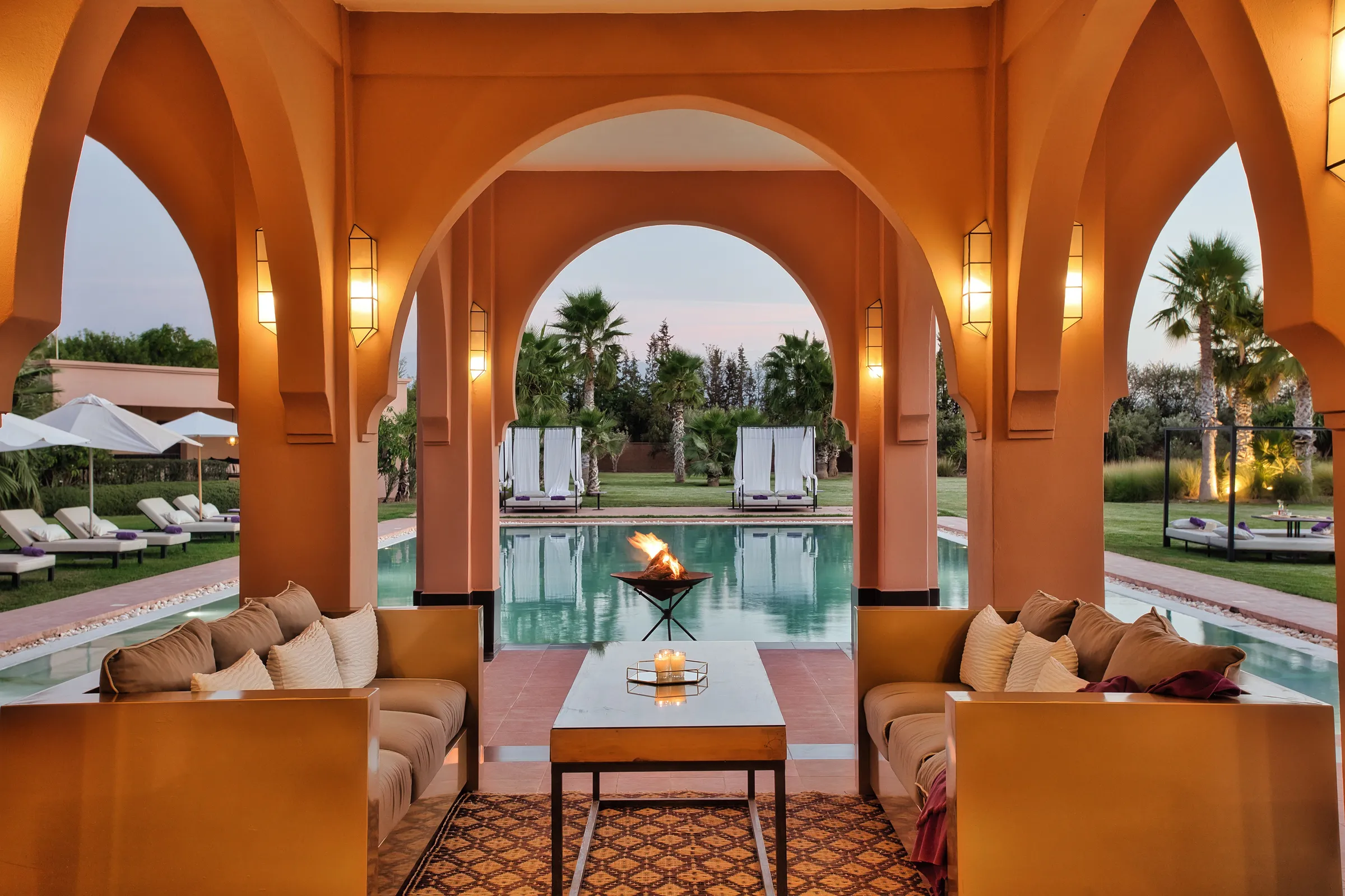 Villa Theia, private villa rental on the Route de l'Ourika, Marrakech: covered terrace lounge with sofas and fire bowl facing the pool