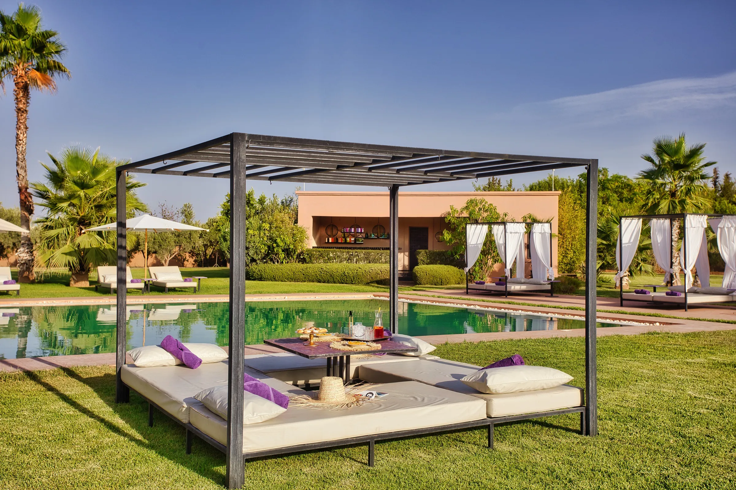 Villa Theia, private villa rental on the Route de l'Ourika, Marrakech: shaded canopy daybed on the lawn beside the pool