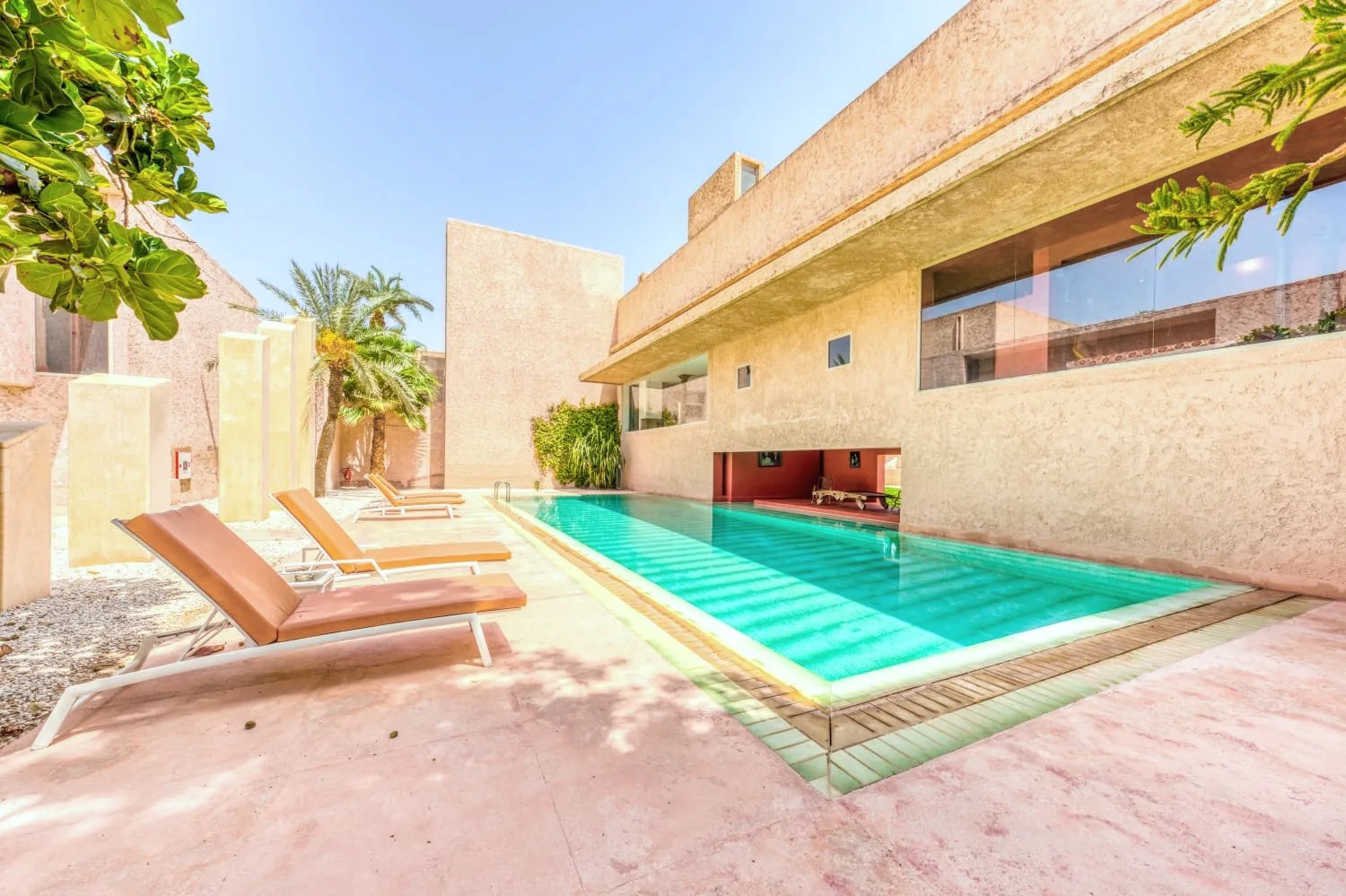 Villa Ianthe, private villa rental in the Palmeraie, Marrakech: pool and loungers along the ochre architecture