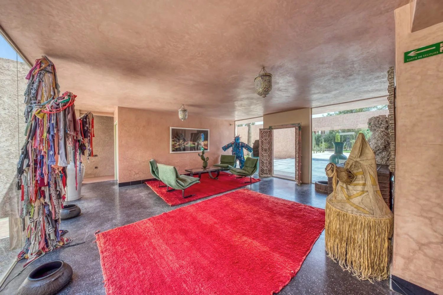 Villa Ianthe, private villa rental in the Palmeraie, Marrakech: salon with red rug and contemporary sculptures