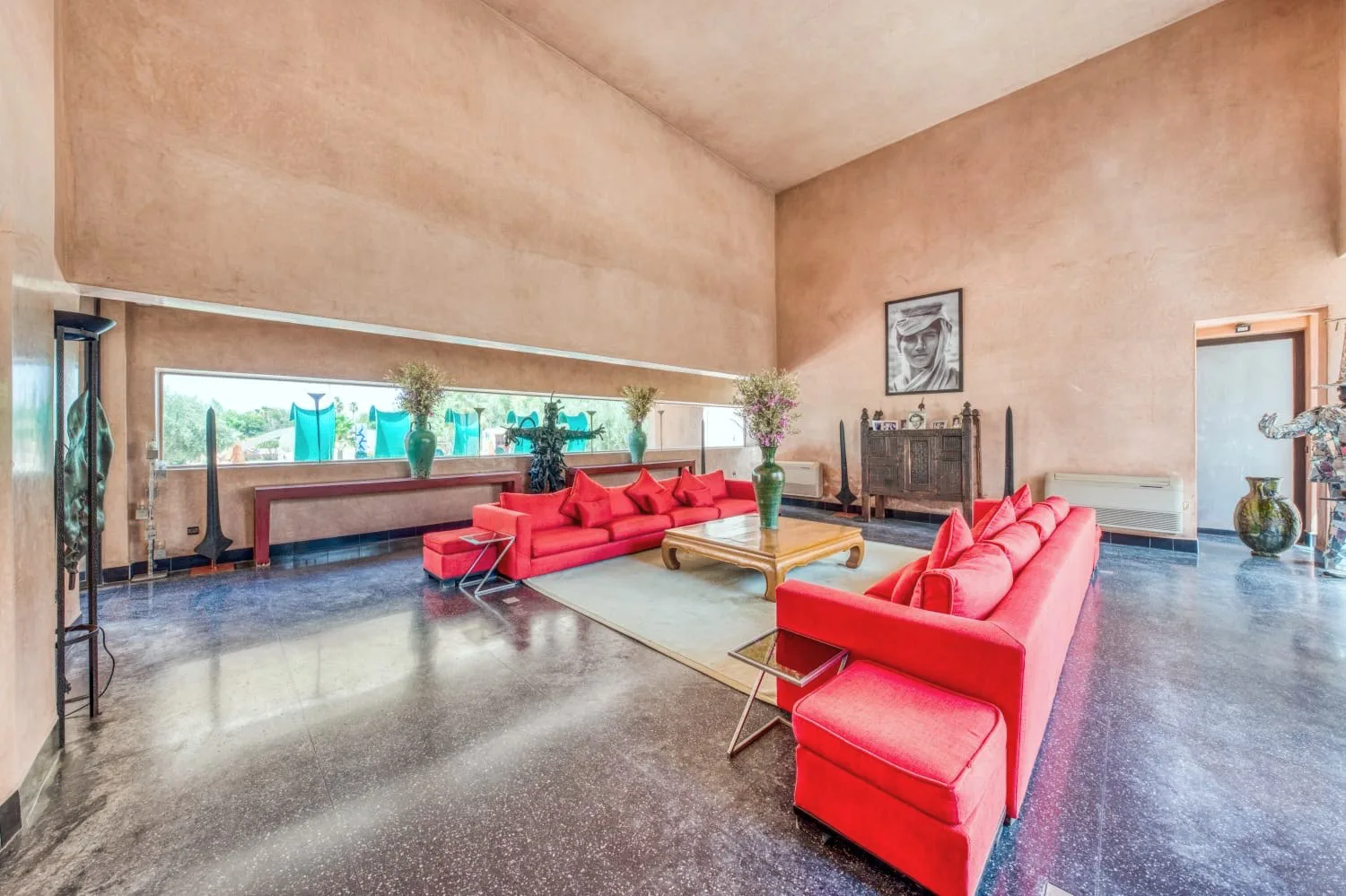 Villa Ianthe, private villa rental in the Palmeraie, Marrakech: double-height salon with red sofas and contemporary art
