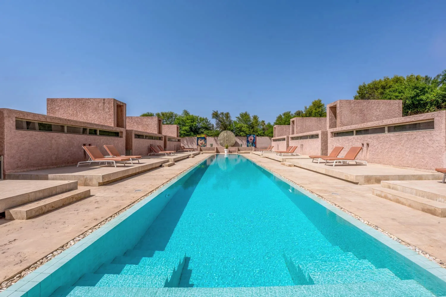 Villa Ianthe, private villa rental in the Palmeraie, Marrakech: long pool between cubist ochre pavilions