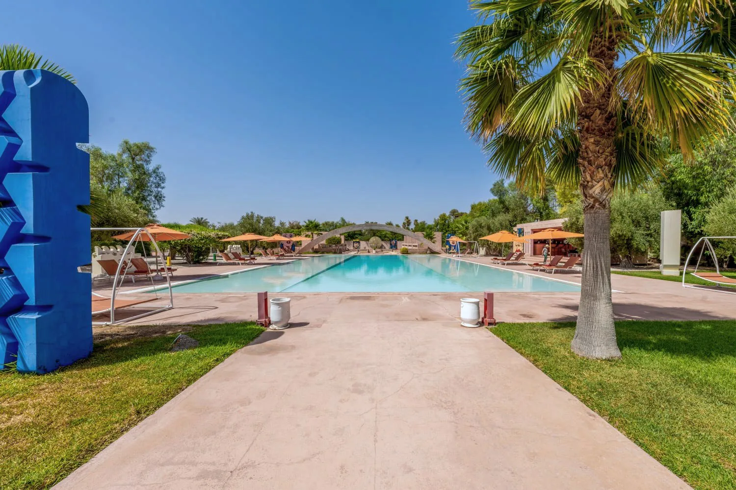 Villa Ianthe, private villa rental in the Palmeraie, Marrakech: garden path leading to the pool past a blue sculpture