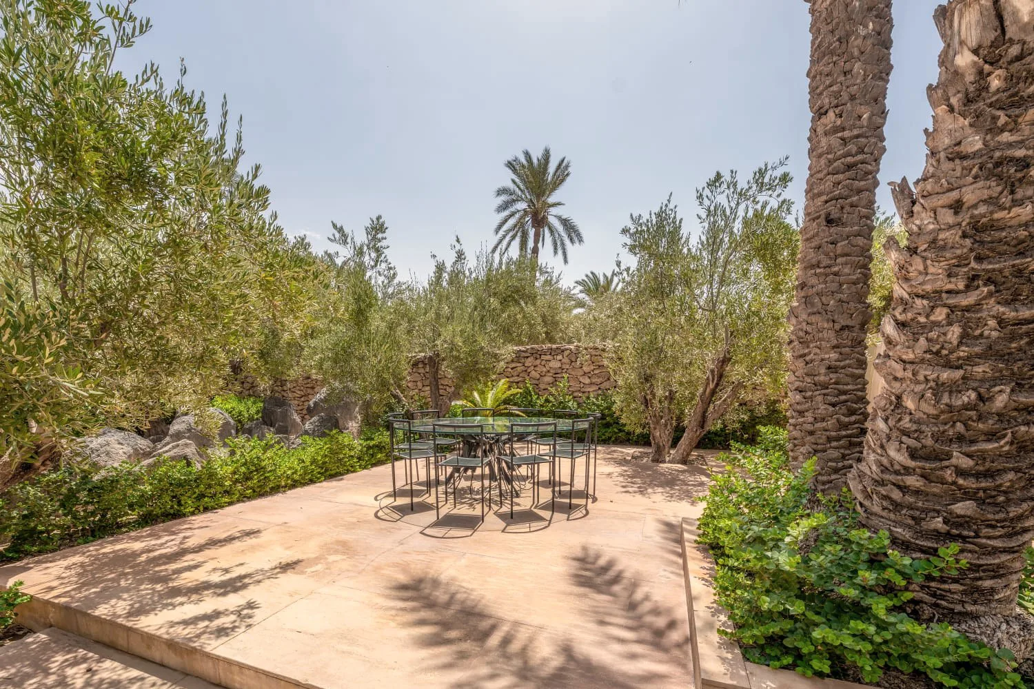 Villa Ianthe, private villa rental in the Palmeraie, Marrakech: garden table in the shade of olive and palm trees