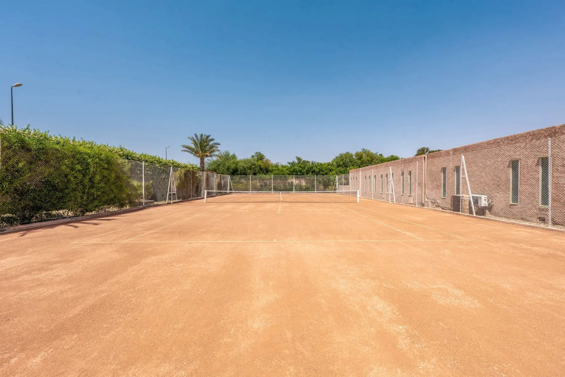 Villa Ianthe, private villa rental in the Palmeraie, Marrakech: clay tennis court surrounded by greenery
