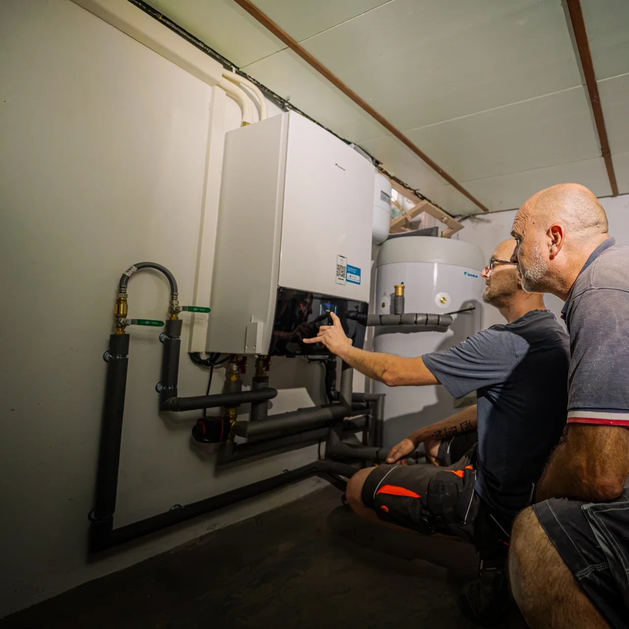 Techniciens réglant le module intérieur d’une pompe à chaleur air-eau Daikin installée dans un sous-sol