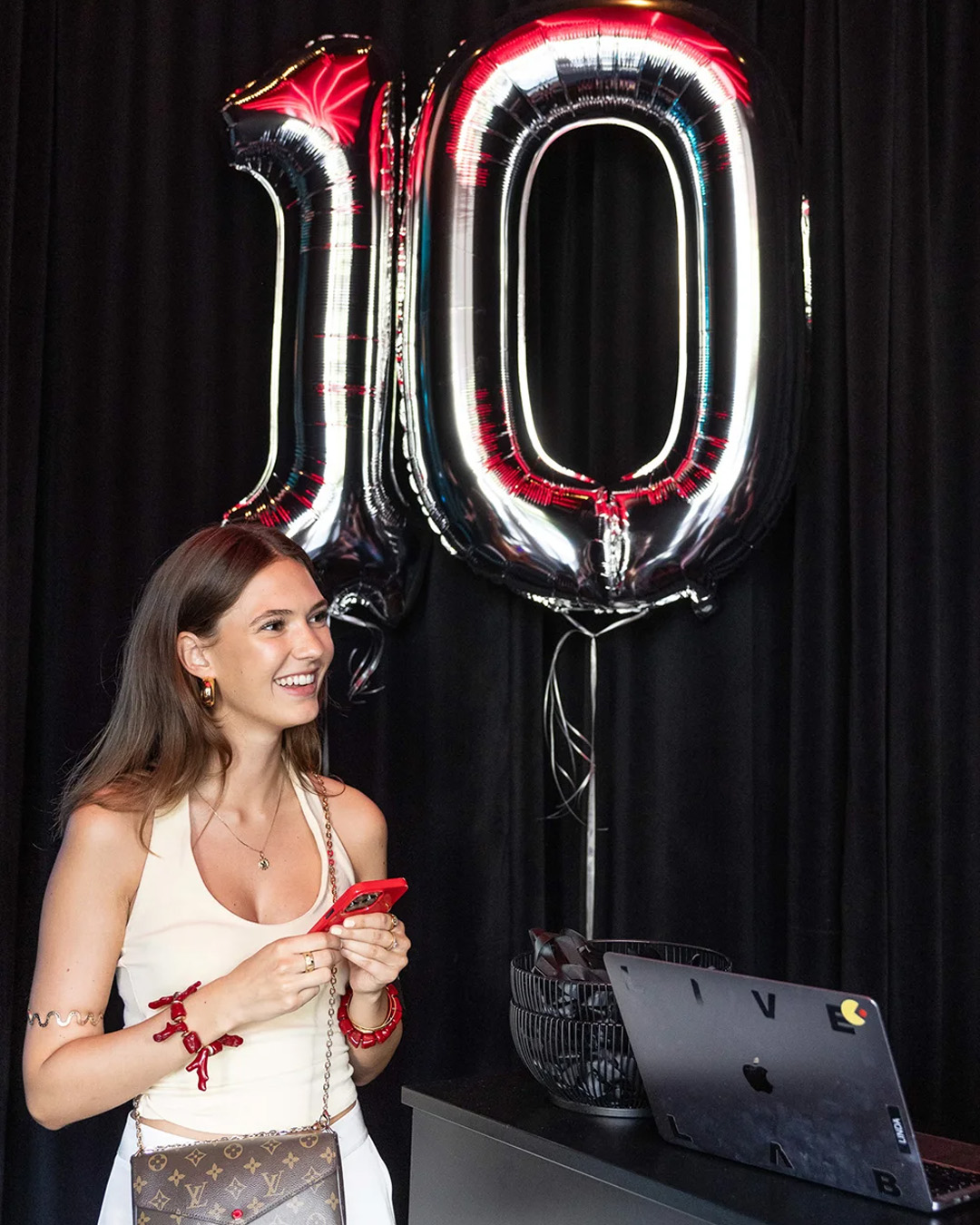 Woman in front of balloons shaped like the number 10