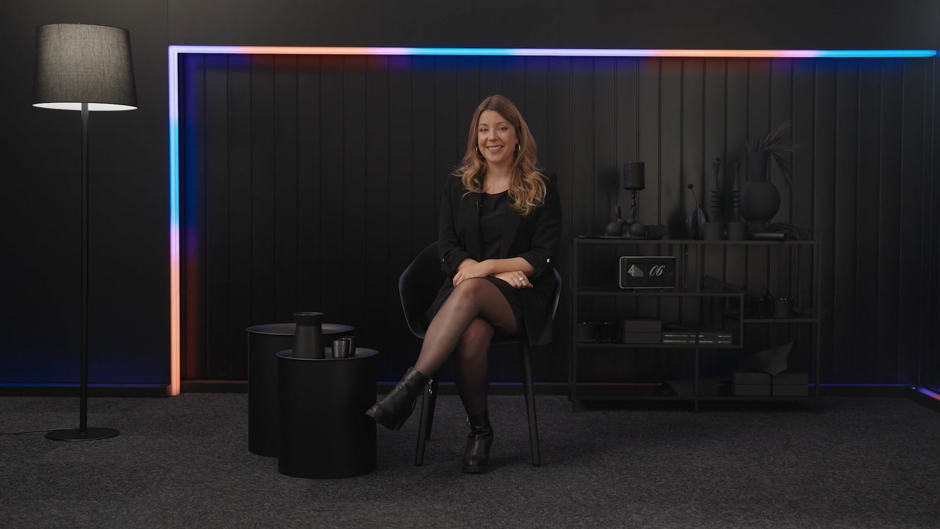 Person in einem stilvoll gestalteten Studio-Setting mit dunkler Einrichtung und farbigen Lichtakzenten. Die Szene vermittelt eine professionelle und moderne Markenkommunikation im Videoformat.